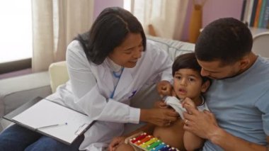 Çocuk doktoru, evde babasıyla birlikte çocuğu muayene ediyor.