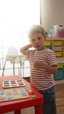 Sarışın çocuk okul bahçesinde renkli yapboz parçalarıyla oynuyor.