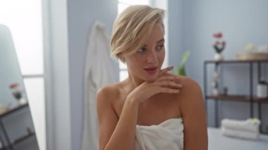 Kısa sarı saçlı genç bir kadın sağlık dekoruyla çevrili bir spa merkezinde dinleniyor.