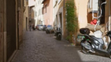 Roma 'daki bulanık yaya sokağı. Parlak renkleri ve park etmiş scooterları olan bir mimari..