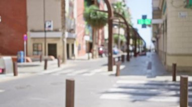 Bulanık binaların, park edilmiş arabaların ve tabelaların yer aldığı sokak manzarası, sanatsal efekt için odaklanmış arka plan elementlerinin bulunduğu kentsel alanda güneşli bir günü gözler önüne seriyor