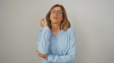 Kolları çapraz duran genç sarışın kadın, yorgun ve sıkılmış görünüyor, tenha beyaz arka plandaki depresyon sorunlarını düşünüyor.