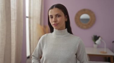 Sıcak bir apartman dairesinde elinde kırmızı bir kalp eşyasıyla gülümseyen İspanyol kadın.