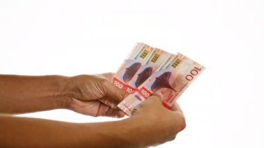 Elleri, beyaz izole edilmiş arka planda Norveç kronu banknotları tutuyor