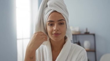 Kafasında havlu ve bornoz olan bir kadın spa odasında güzellik ve rahatlık sergiliyor.