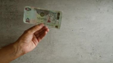 Birleşik Arap Emirlikleri 'nin el ele tutuşması beton bir duvara karşı, düz bir ortamda para gösteriyordu..