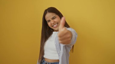 Kadın kendinden emin bir şekilde gülümsüyor, parlak sarı bir arka plana karşı, neşeli pozitiflik ve çekicilik yayıyor, başarı ve mutluluk kavramları için mükemmel..