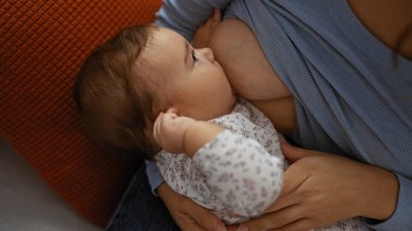 Anne sıcak oturma odasında bebeği emziriyor, sevgi ve bağlılık gösteriyor, sıcak ev ortamında bebekle ilgilenen bir kadınla..