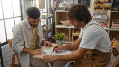Adam ve fırıncı pastanenin içindeki bir masada belgeleri tartışıyorlar.