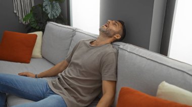 Adam modern bir kanepede rahat rahat rahat bir oturma odasında rahat yastıklar ve doğal ışık evinde huzurlu bir atmosfer yaratıyor..