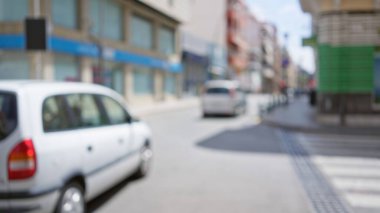 Blurred background of a city street with cars and buildings captured out of focus with bokeh effect in daytime clipart