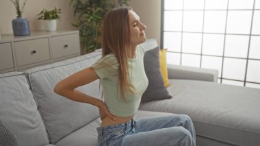 Genç, çekici, sarışın bir kadın şık bir oturma odasında oturuyor, içeride, onu rahatsız ediyor..