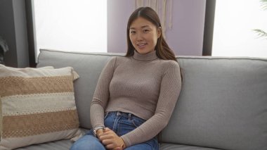 Kadın rahat bir evde, rahat bir oturma odasında kanepede dinleniyor. İçeriden güzellik ve sükunet yayıyor. Uyumlu ve rahat bir iç mekan sergiliyor..