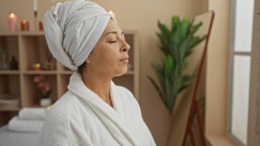 Kafası ve gözleri kapalı, sakin bir kaplıca odasında dinlenen bir kadın, evde sükunet ve sükuneti kucaklıyor.