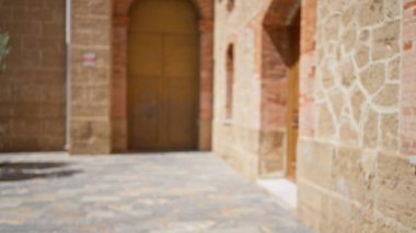 Tuğla duvarları, kaldırım taşı yolu ve güneşli bir kentsel alanda Bokeh etkisi olan kemerler olan bulanık bir açık hava sahnesi.