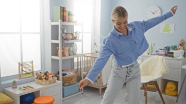 Parlak bir yatak odasında oyuncaklarla çevrili, gülümseyen ve dans eden genç bir kadın, rahat bir yuva ortamında neşeli bir ev hayatı sergiliyor..