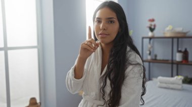 Kaplıca elbiseli güzel bir kadın, uzun esmer saçlı, sakin bir sağlık odasında, yukarı bakıyor ve ileriye bakıyor..