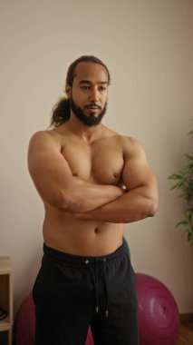 Sakallı bir adam, sağlık merkezinde çapraz silahlanmış. Huzurlu bir kaplıca ortamında kendine güven ve rahatlama yayıyor..