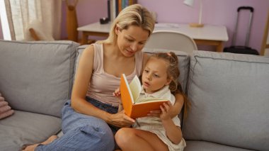 Oturma odasındaki kanepede kitap okuyan bir kadın.
