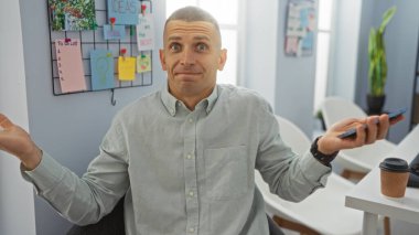 Ofisteki genç adam elinde notlar ve fikirlerle şaşkın şaşkın bakıyor.