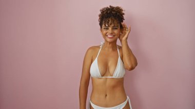 İzole edilmiş pembe arka planda beyaz bikinili güzel bir İspanyol kadın.