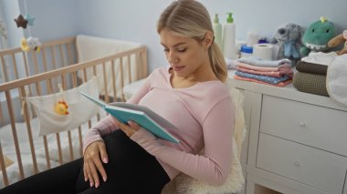 Bebek beşiği ve yumuşak ışıklandırmasıyla rahat bir yatak odasında kitap okuyan hamile bir kadın, bebek aksesuarlarıyla çevrili, sıcak ve huzurlu bir atmosfer yaratıyor..