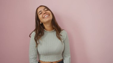 Soyutlanmış pembe arka planda gülümseyen bir kadın, genç, güzel, esmer, İspanyol bir kadını gösteriş yapıyor..