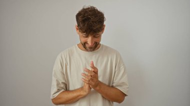 Genç adam gülümsüyor ve ellerini izole edilmiş beyaz arka planda tutuyor.