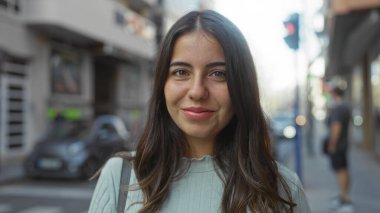 Şehirdeki bir sokakta gündüz vakti sırıtan esmer saçlı bir kadın günlük hayatın güzel bir anını yakalıyor..