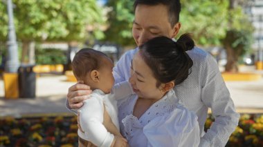 Anne, baba ve oğlanla aile şehir parkında birlikte vakit geçiriyorlar. Şehir ortamında sevgi ve mutluluk yayıyorlar..