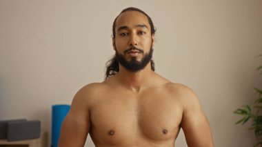 Sakallı genç adam sağlık kaplıcasında duruyor, sakin bir atmosfer sergiliyor. Rahatlama ve meditasyon için ideal, çağdaş tasarım unsurlarıyla birlikte..