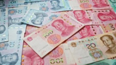 Çeşitli mezhepleri içeren Çin yuanı banknotları, Çin 'in para birimini canlı renklerle ve ayrıntılı tasarımlarla vurgulayan dağınık bir desen içinde dağılmış durumdadır..