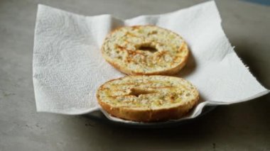 Beton yüzey üzerinde kağıt havlu üzerinde iki kızarmış simit. Hafif gölgeli, doku detaylarını gösteren ve basit bir mutfak ortamında çıtır çıtır bir yüzey.