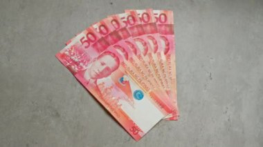 Filipin banknotları, belirgin detaylar ve canlı renklerle 50 peso değerinde beton bir yüzey üzerinde düzenlenmiş..