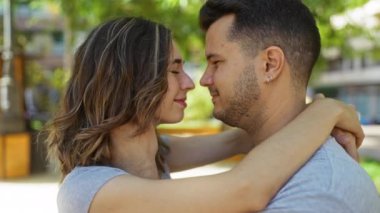 Couple embracing in outdoor urban park with trees in background portraying love and affection