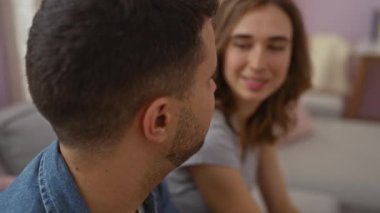 Sıcak bir oturma odasındaki kanepede oturan çift, yakın ve gülümsüyor.