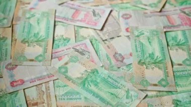 Çeşitli mezhepler ve karmaşık tasarımlar içeren birden fazla uae dirham banknotları bir yüzeye saçılmış..