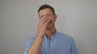 Yüzü beyaz duvara dönük gülümseyen genç adam, açık mavi gömleğiyle mutluluk ve tefekküre dalıyor.