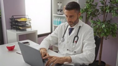 Doctor celebrating success with raised fists sitting at desk in clinic, showing a joyful expression in a professional medical environment.