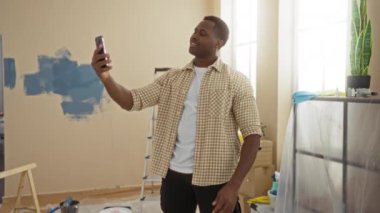 Yenilenme sırasında evdeki genç adam videosu neşeli bir ifadeyle modern parlak apartmandaki kutuları ve aletleri taşırken hayat değişiyor..