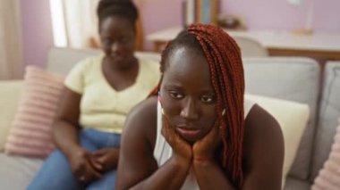 Oturma odasındaki kanepede tartışan iki kadın. Biri üzgün, diğeri endişeli görünüyor.