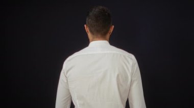 Siyah arka planda beyaz gömlekli genç adam kendine güvenen profesyonel kişiliğini sergiliyor.