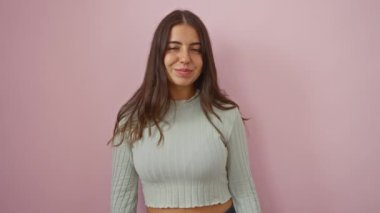 Elleri göğsünde pembe bir arka planda gülümseyen bir kadın, izole edilmiş bir stüdyo ortamında esmer bir kadın, yumuşak bir ifade ve tırtıklı bir süveter ile minnettarlığını gösteriyor..