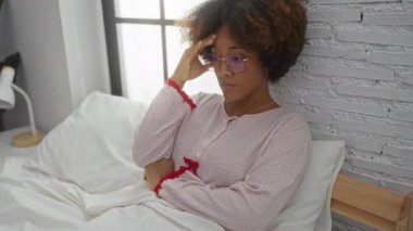 Parlak bir odada gözlüklü, kıvırcık saçlı, dalgın dalgın dalgın dalgın ve endişeli bir kadın.