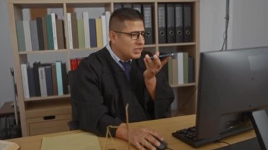 Ofisteki genç İspanyol adam yargıç cübbesi giyiyor. Arkasındaki kitaplıklarla telefonda konuşuyor.