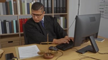 Yargıç cüppeli genç İspanyol adam evrak okuyor ve ofisteki klavyede bilgisayar, terazi ve kitaplık ile daktilo kullanıyor..
