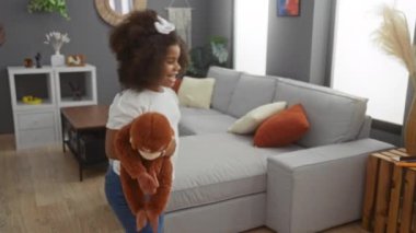 Baba ve kızı evde rahat bir oturma odasında oyuncak tutuyor yumuşak renkler ve rahat mobilyalar ile sıcak bir aile ortamı yaratıyor sevgi ve birlikteliği yansıtıyor..