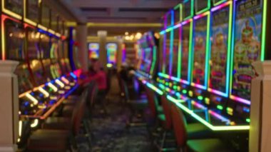 Canlı bir Las Vegas kumarhanesindeki renkli kumar makineleri arka planda bulanık figürlerle heyecan verici bir atmosfer yaratıyor..