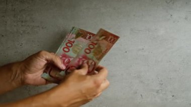 Yeni Zelanda doları banknotları tutan adam somut arka plan, döviz kurunun altını çizmek veya finansal konsept.