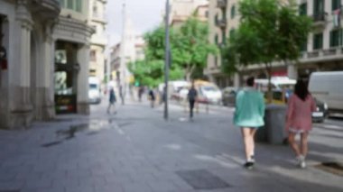 Barselona, İspanya 'daki bulanık şehir sokak manzarası, açık gökyüzü altında trafiğin ve tarihi mimarinin önünden geçen insanların görüntüsü..